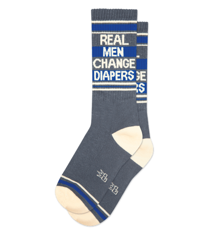 Charcoal gray socks with royal blue accents, text reads "Real Men Change Diapers." Cream toe and heel.