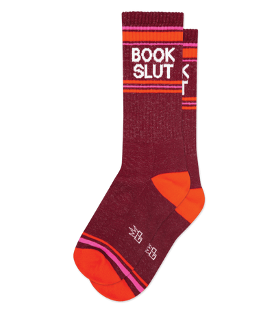 Crimson socks with "BOOK SLUT" in white text, orange accents, and pink stripes on the cuffs and toes.